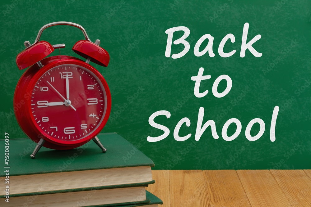 Back to School message with alarm clock on books with a chalkboard Back to School message with alarm clock on books with a chalkboard