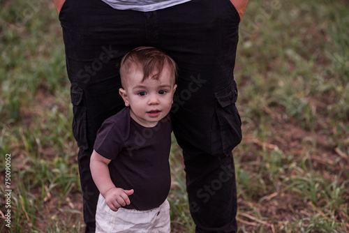 Close-up portrait of small boy looking curiously ahead while being held securely by parents hand, evoking sense of growing independence. Guided First Steps. Child seeks support from father. photo