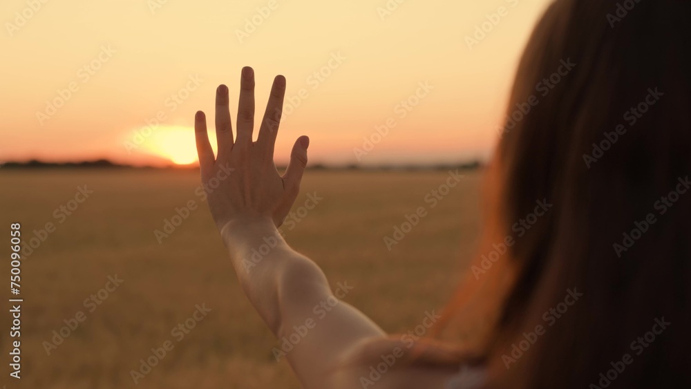 Happy girl stretches her hand to yellow sunset. Sun between fingers of girls hands. Teenager girl with long hair holds out her hand at sun. Childhood dream, express emotions, nature. Symbol travel