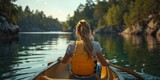 A woman rows a canoe on a serene lake, surrounded by nature, capturing the essence of adventurous relaxation.