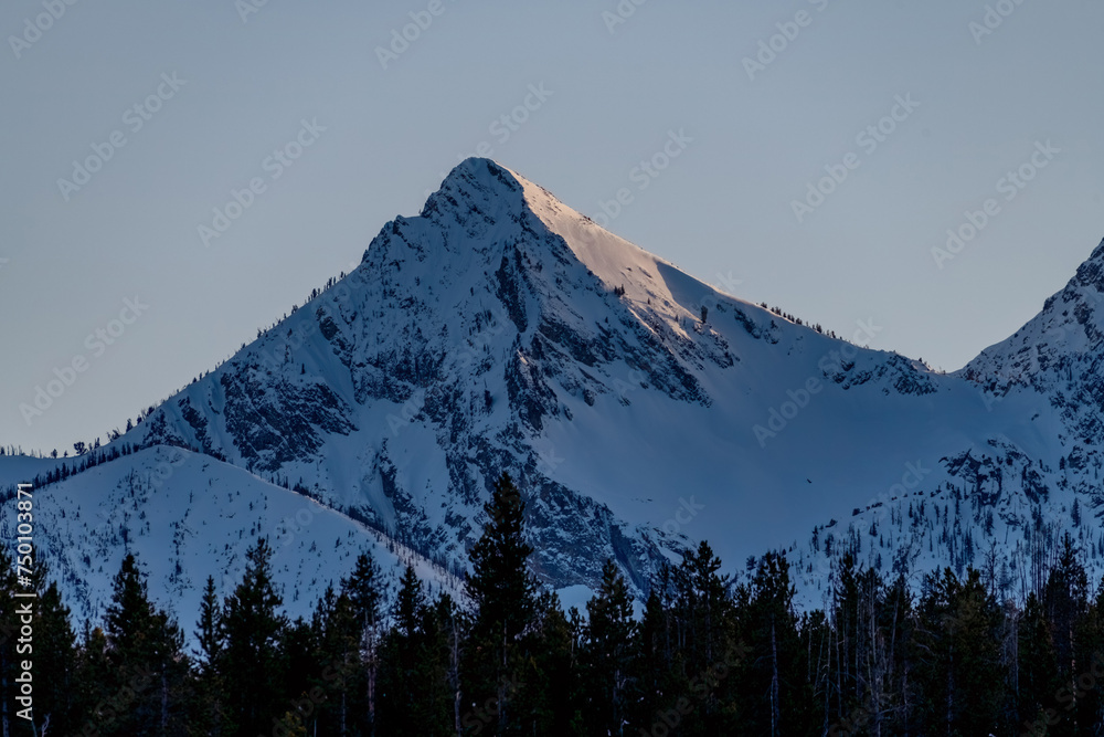 High snow covered mountain peak with sunset light on it High snow covered mountain peak with sunset light on it
