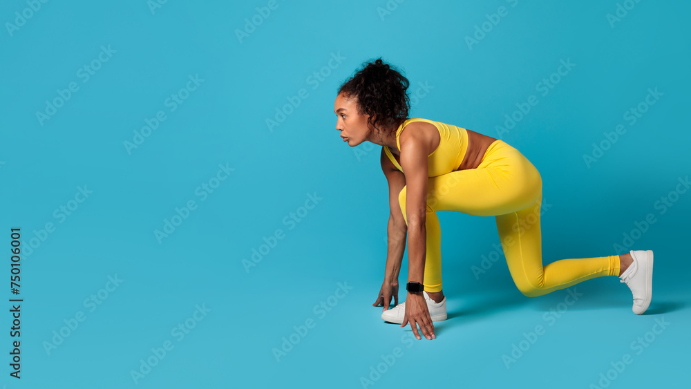 black woman confidently posing in crouch position on blue background
