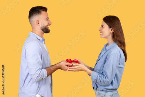 Man giving red-ribboned gift to delighted woman