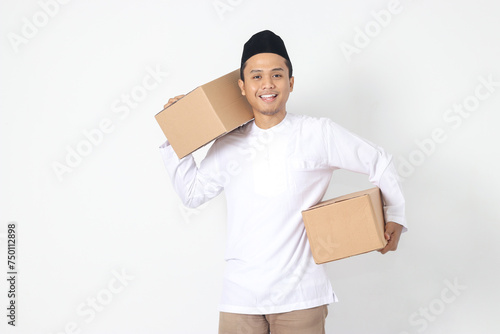 Portrait of happy excited Asian muslim man going home for Eid Mubarak. Indonesian guy carrying cardboard box. Isolated image on white background photo