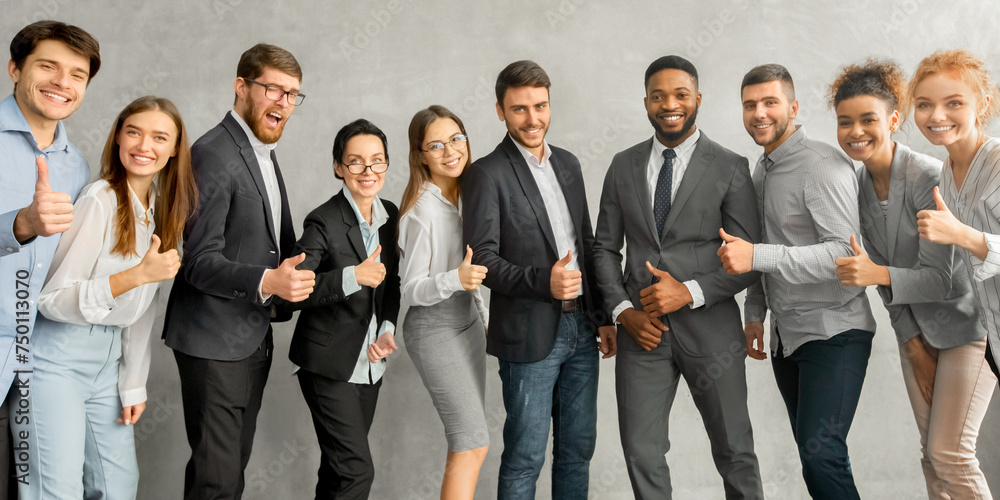 Cheerful young business team showing thumbs up