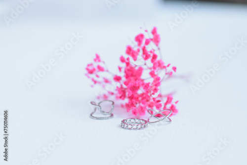 Fototapeta Naklejka Na Ścianę i Meble -  silver rings lie on a white surface with pink flowers