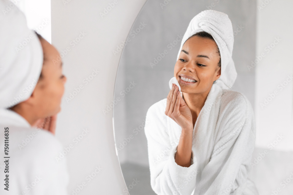 Black lady using cosmetic applying with cotton pad at bathroom Black lady using cosmetic applying with cotton pad at bathroom