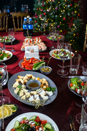 Set of dorblu cheese, parmesan, brie cheese, honey and walnuts, Greek salad of fresh cucumber, tomato, sweet pepper, lettuce, red onion, feta cheese and olives on table.