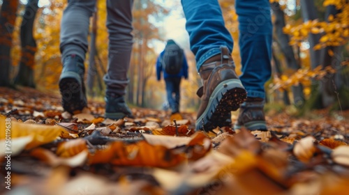 Two individuals are walking down a path covered in fallen leaves