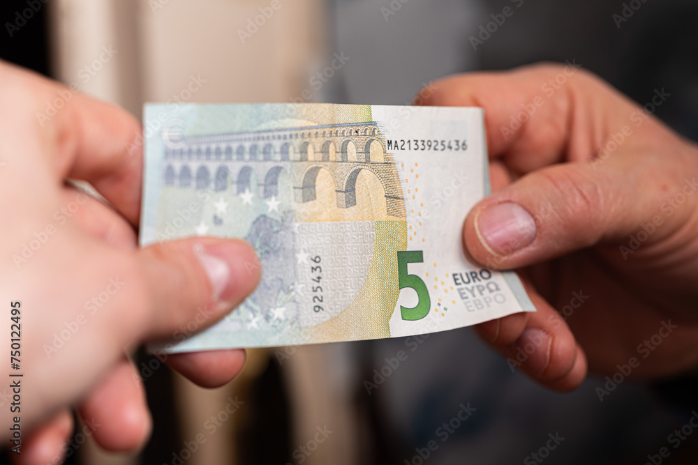 concetto di scambio di denaro. visuale in primo piano sulle mani di due persone caucasiche che si scambiano una banconota da 5 euro - obrazy, fototapety, plakaty 