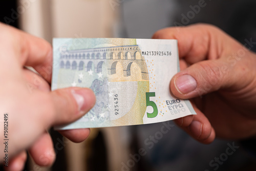 concetto di scambio di denaro. visuale in primo piano sulle mani di due persone caucasiche che si scambiano una banconota da 5 euro photo