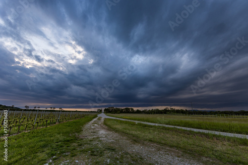 ampia visuale panoramica che mostra una immensa supercella temporalesca, con nuvole molto scure, che si sposta sopra la pianura orientale del Friuli Venezia Giulia, al tramonto photo