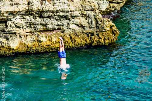 Young boy diving headfirst from the rocks into the sea at the famous Cala En Brut in Menorca, Balearic Islands, Spain