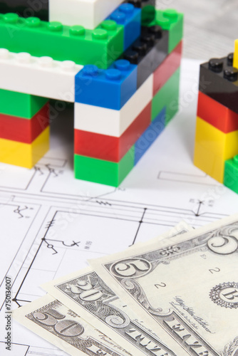 Small houses made of toy blocks, electrical diagrams of house and dollar banknotes. Building home costs