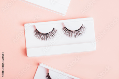 Different fake eyelashes in boxes on trendy pastel pink background. Makeup accessories. cosmetics products for women. Top view, flat lay. Layout. Place for text and design.