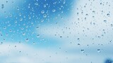 Raindrops create patterns on glass against a backdrop of blue and white skies.