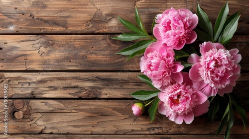 a bouquet of pink flowers sitting on top of a wooden table next to a green leafy plant on top of a wooden table. photo