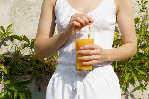 Konstfotografi a young woman holds a glass of orange juice and a paper tube in front of her