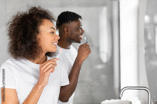 Side view portrait of black young couple brushing teeth indoor