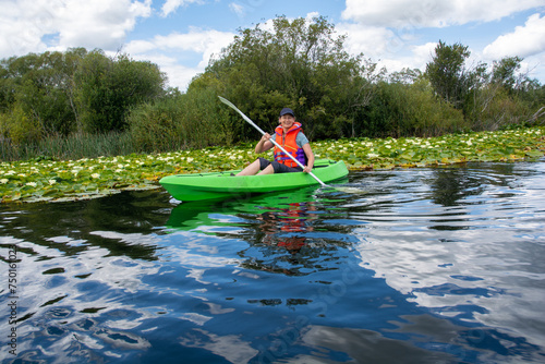 Lady paddles a Kayak near water lilies in New Zealand