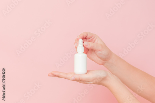 Glass cosmetic bottle for serum  hyaluronic acid and collagen  in hand on pink background. Beauty concept