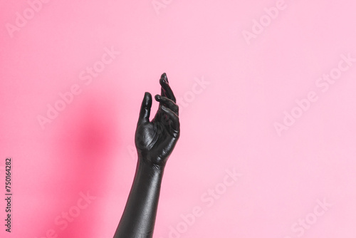 Elegant woman's hand with black paint on her skin on pink background. High Fashion art concept