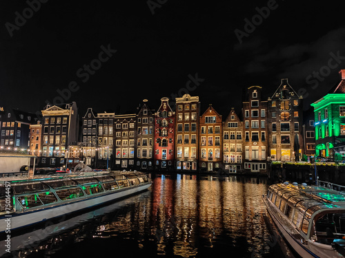 Amsterdam night cityscape over the water. Famous Dutch dancing houses reflecting in the canal