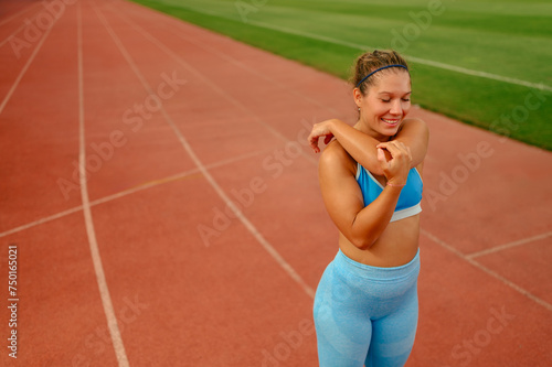Portrait of a young woman stretching her arms and shoulders at the stadium © Zamrznuti tonovi