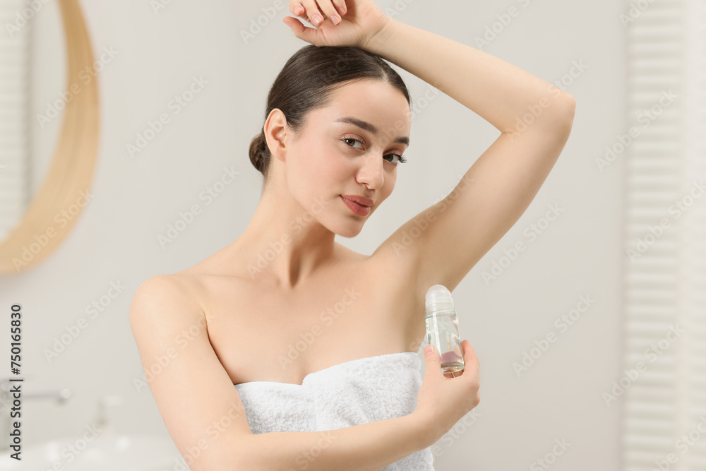 Beautiful young woman applying deodorant in bathroom Beautiful young woman applying deodorant in bathroom