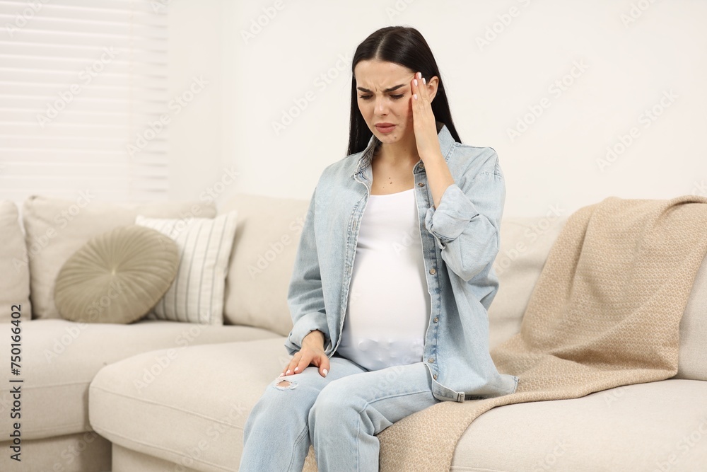 Pregnant woman suffering from headache on sofa at home Pregnant woman suffering from headache on sofa at home