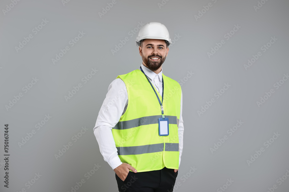 Engineer with hard hat and badge on grey background