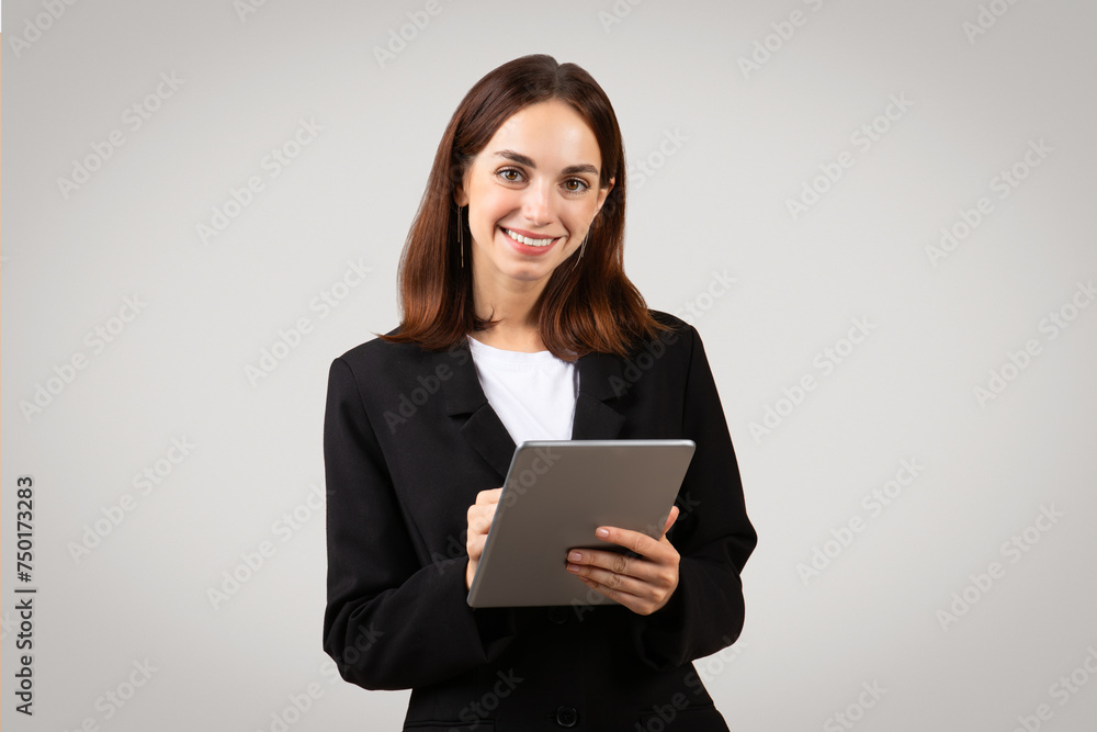 A poised and professional young woman with a warm smile confidently holds a tablet A poised and professional young woman with a warm smile confidently holds a tablet