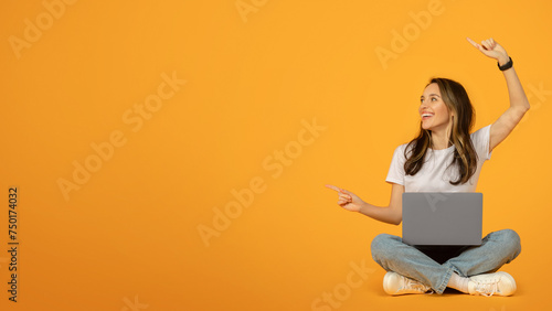 Joyful woman in white t-shirt and blue jeans sitting with legs crossed on the floor © Prostock-studio