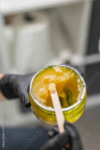 Orange body scrub with sugar and oil in glass jar in female hand. Homemade cosmetic for peeling and spa care. Copy space and empty place for advertising