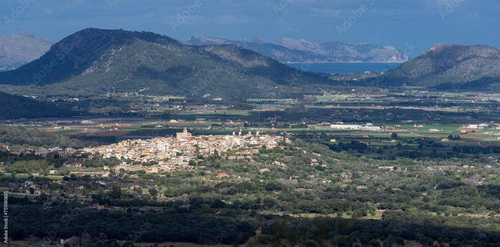 Scenic Aerial View of Campanet Village in Mallorca Amidst Lush Greenery and Mountain Backdrop