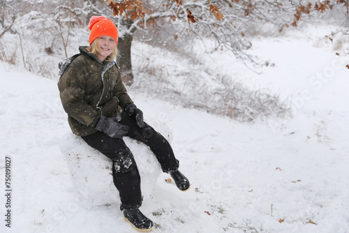 Happy Kid Sitting on Giant Snow Boulder Outside on a Winter Day