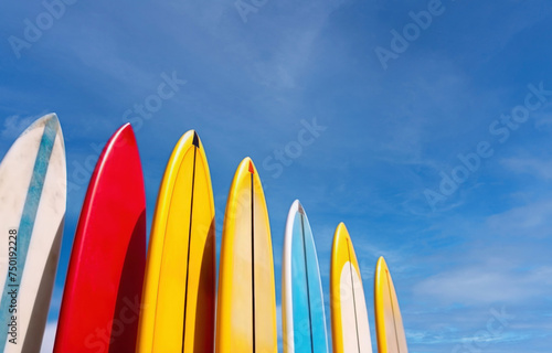 Set of differently colored surfboards stacked by the ocean photo