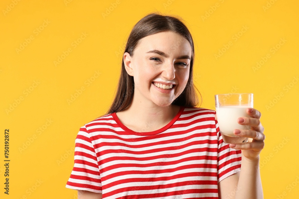 Happy woman with milk mustache holding glass of tasty dairy drink on orange background Happy woman with milk mustache holding glass of tasty dairy drink on orange background