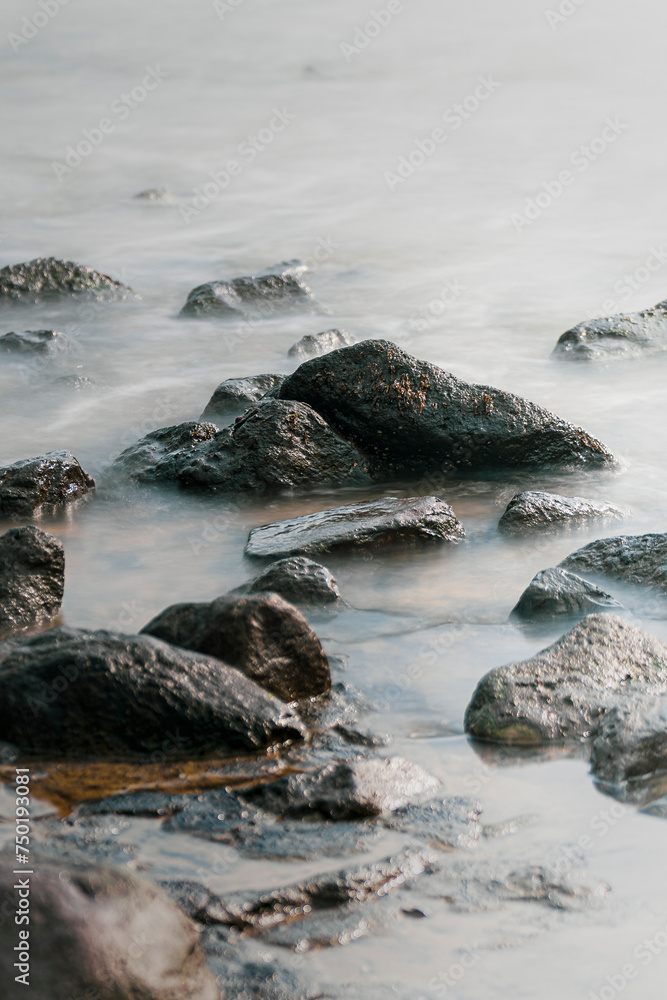 Cobblestones and rocks along the seacoast with smooth water through long exposure shot Cobblestones and rocks along the seacoast with smooth water through long exposure shot