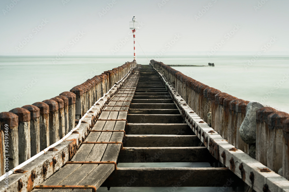 Sea pier with wooden poles and endless horizon of the sea