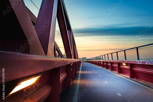 Red railroad bridge named 'Hanzeboog' over the IJssel river in the dutch Delta landscape