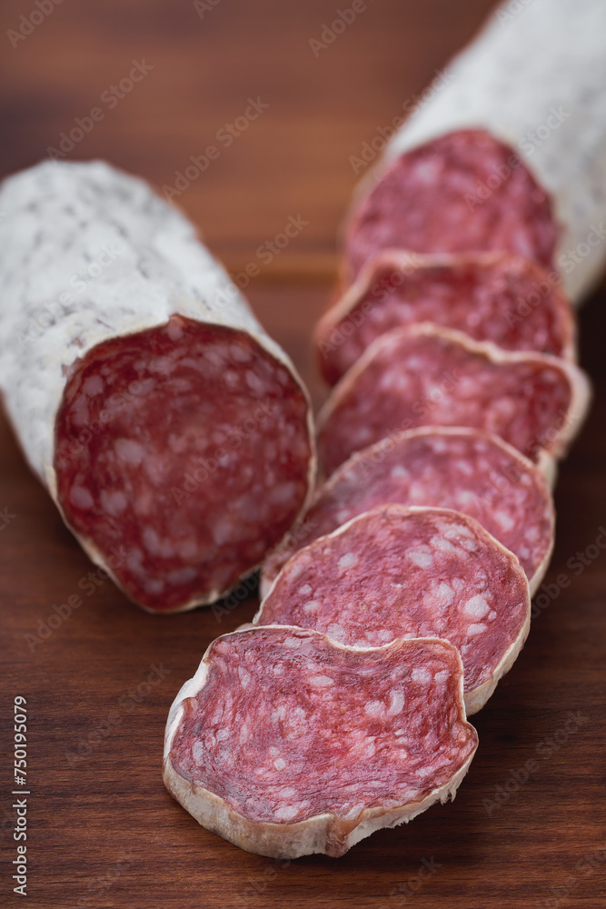 traditional Spanish salami fuet sausage or dry sausage cut in slices in a kitchen table. traditional Spanish salami fuet sausage or dry sausage cut in slices in a kitchen table.