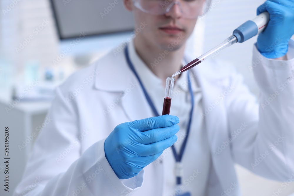 Scientist dripping sample into test tube in laboratory, closeup Scientist dripping sample into test tube in laboratory, closeup