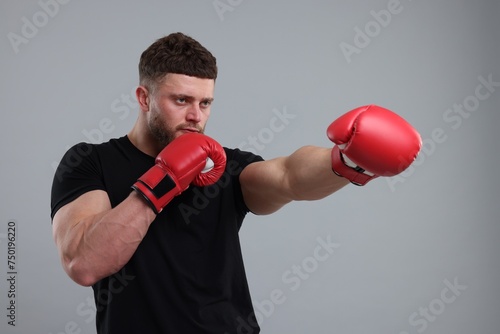 Man in boxing gloves fighting on grey background © New Africa