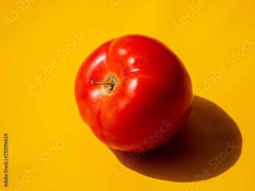 Tomate maduro fondo amarillo luz fuerte