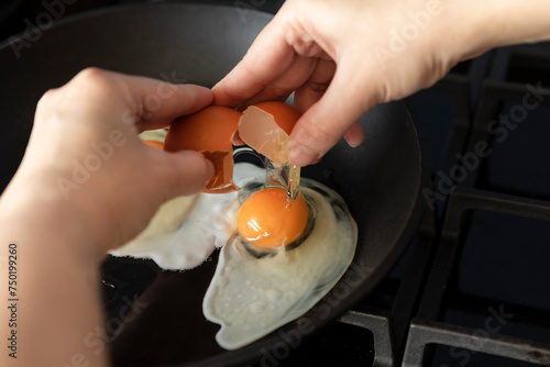 Close-up shot of a woman breaking an egg and preparing scrambled eggs for breakfast