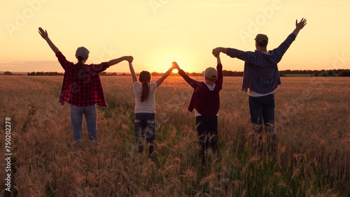 Teamwork of group of people walk in wheat field. Child parents. Group Prayer of Sun. Family holiday. Child mom dad walking holding hands. Happy family of farmers raising their hands outdoors at sunset