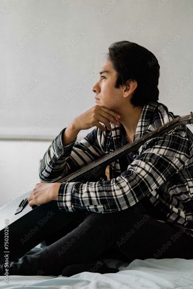 Latin man playing acoustic guitar at home reading notes Latin man playing acoustic guitar at home reading notes