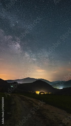 Vertical video of milky way galaxy stars moving over countryside nature landscape astronomy time lapse