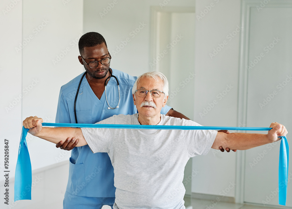 Obraz premium therapist senior man exercise exercising patient physical therapy care nurse recovery physiotherapy fitness stretching stretch band elderly support training